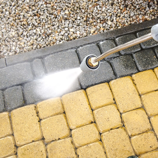 Technician performing Power Washing in Amityville, NY on a stained concrete driveway for a homeowner.